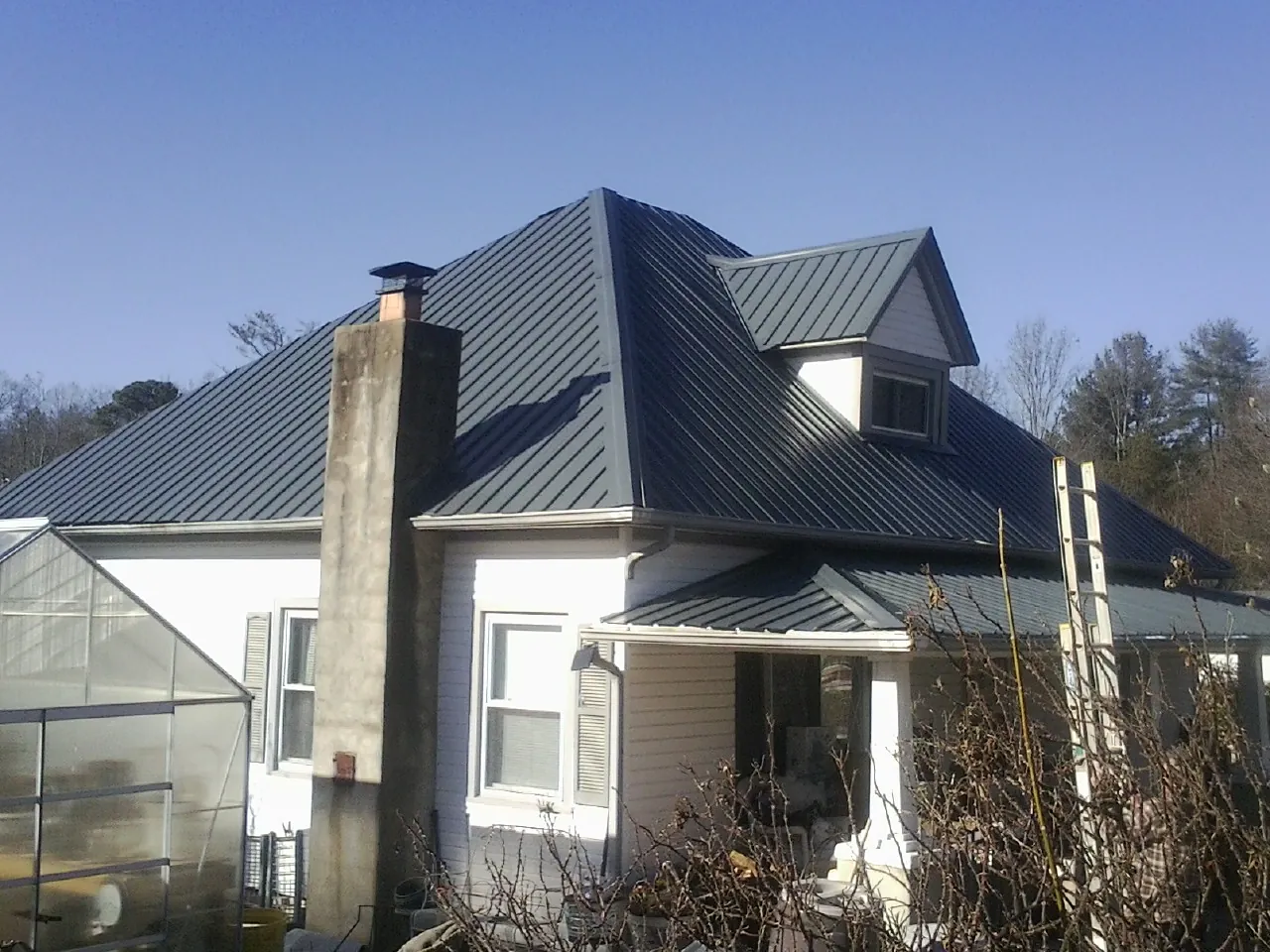 Dark blue standing seam metal roof on a white farmhouse with dormer — Slate & Tile Roof Repair by Roofing Brothers in Sunman