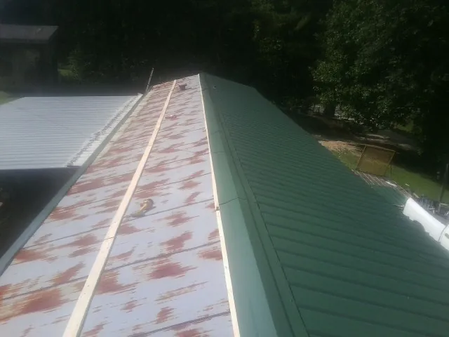 Old rusted panels beside newly installed green metal roofing — Wind Damage Roof Repair by Roofing Brothers in Sunman
