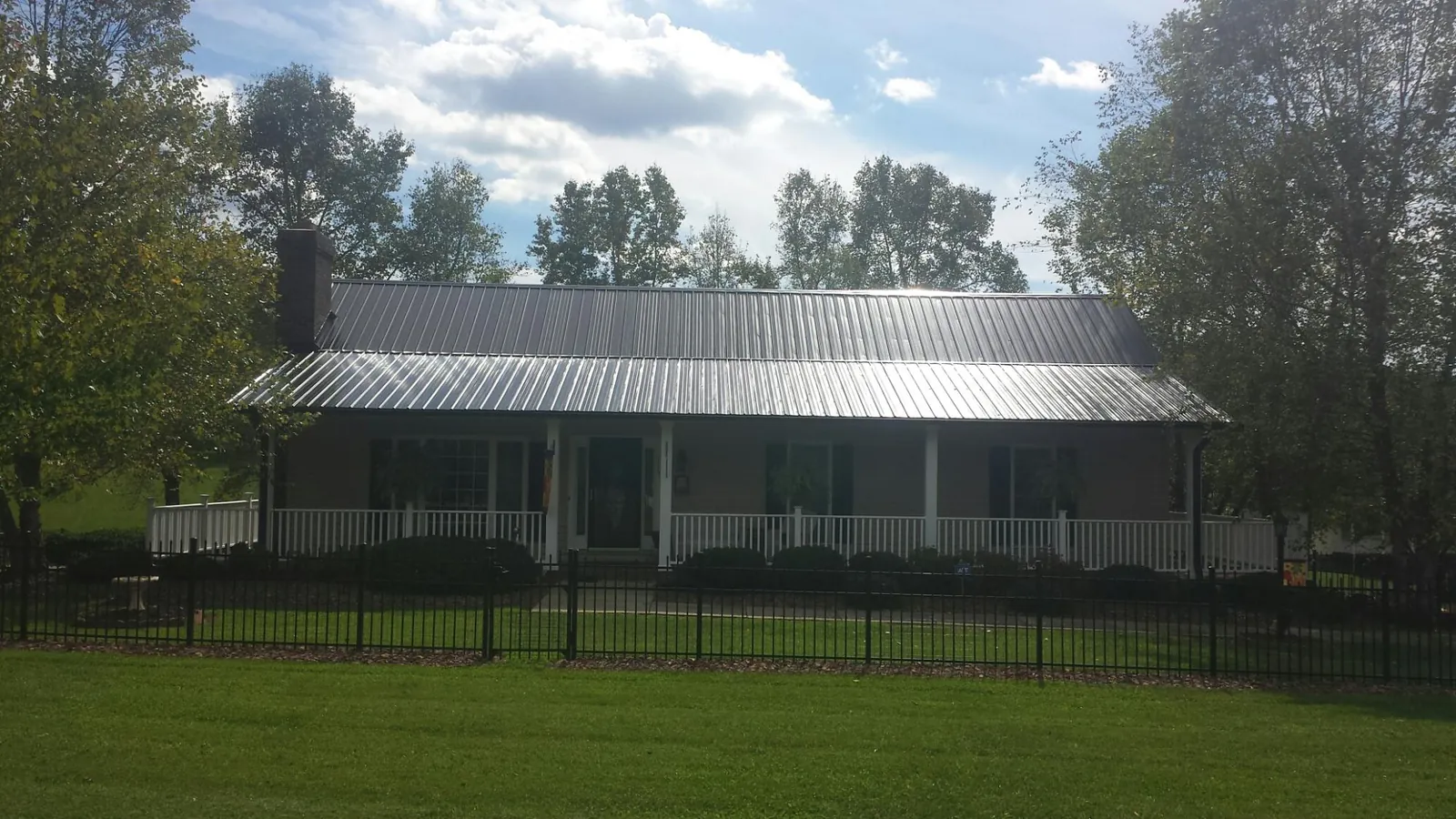 Gray metal roof on a brick ranch with a full width front porch — Gutter Guard Installation work by our crew in Sunman