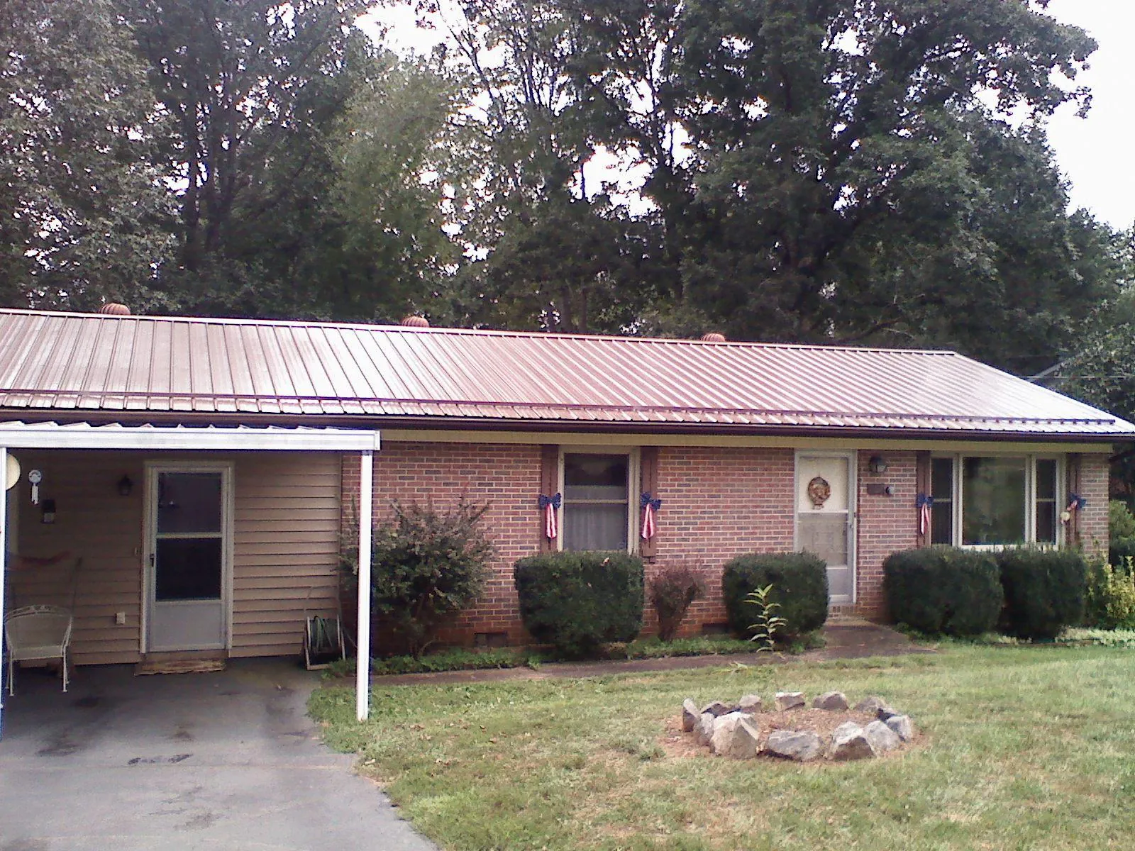 Bronze metal roof and carport on a brick ranch home — Roof Repair work by our crew in Sunman
