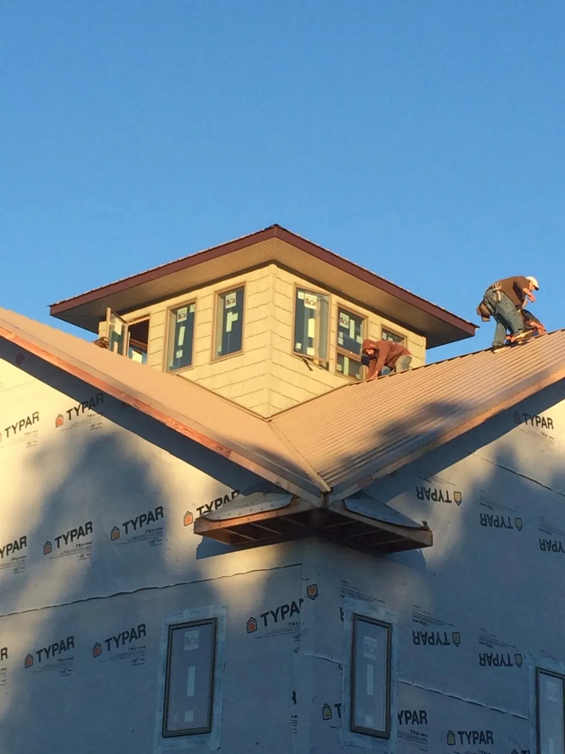 Roofers working around a rooftop cupola on a new metal roof at sunset — Roof Waterproofing in Sunman by Roofing Brothers